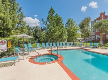Large sundeck with lounge chairs at the swimming pool at Evergreens at Mahan apartments for rent in Tallahassee, FL